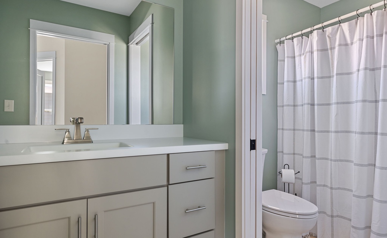 This sleek full bathroom has a shower-soaker tub combo and stone-top vanity.