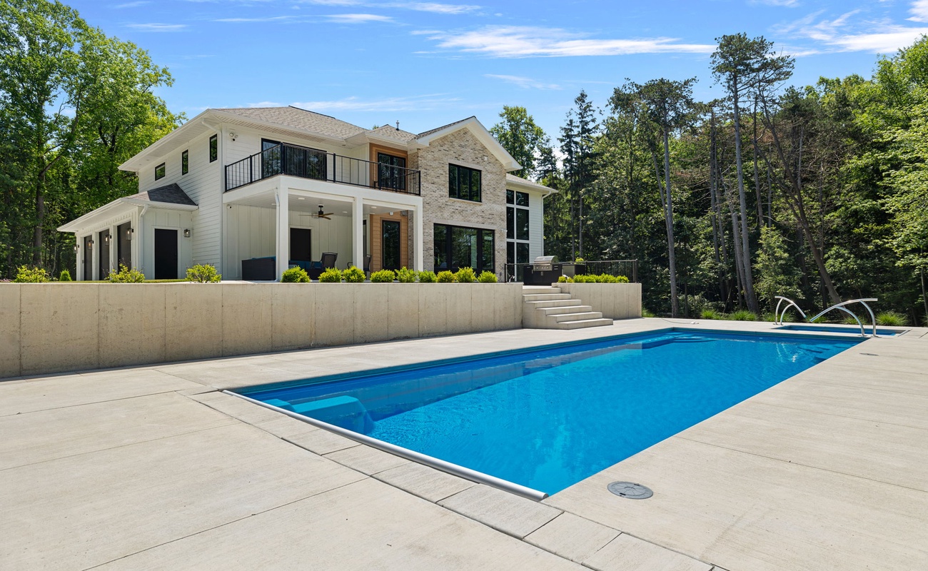 Blue skies, green trees, and a sparkling swimming pool.