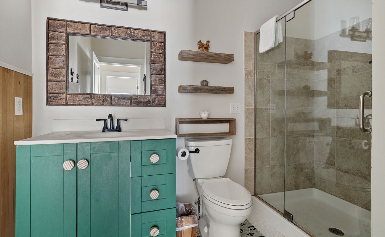 This bathroom features a tiled walk-in shower, stone-top vanity, eclectic decor.