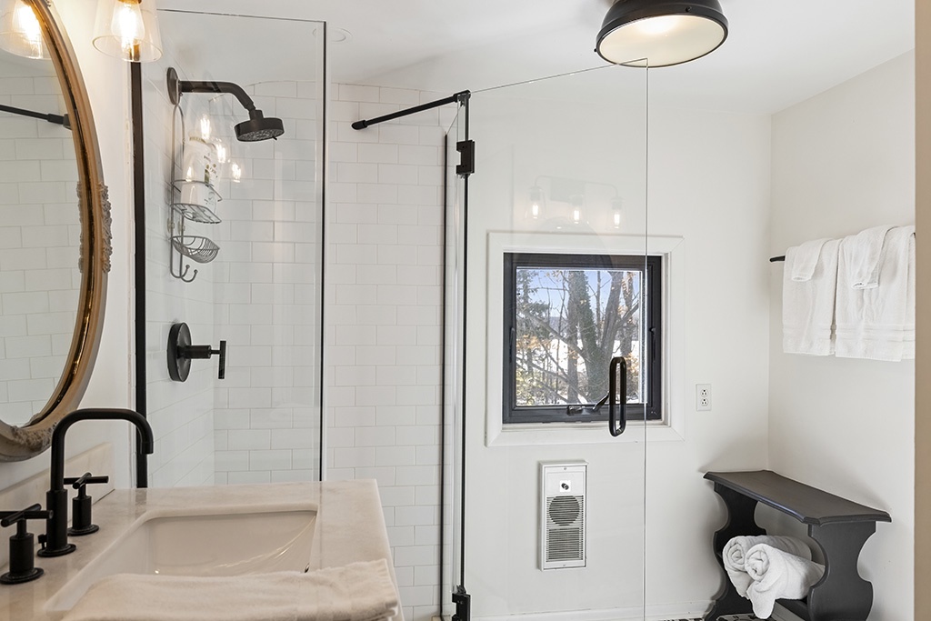 Crisp white tile and matte-black details elevate this serene bath at The Farmhouse.
