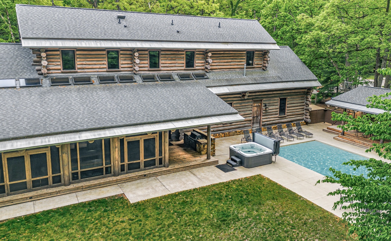 A private log estate with pool, hot tub, and covered lounging in nature.