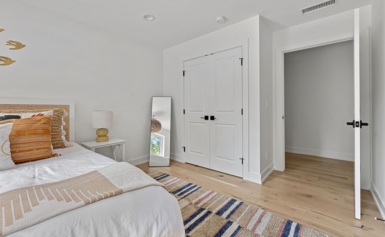Indulge in comfort and style in this stunning bedroom with a luxurious white bed and beautiful wooden flooring for moments of pure relaxation.