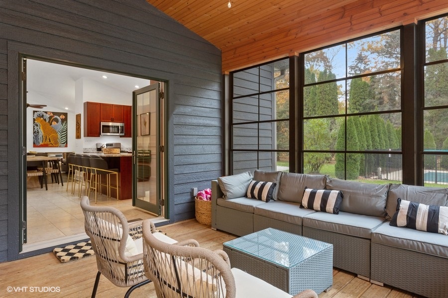 Transition to the cozy porch with wall-to-wall windows for additional outdoor living space.