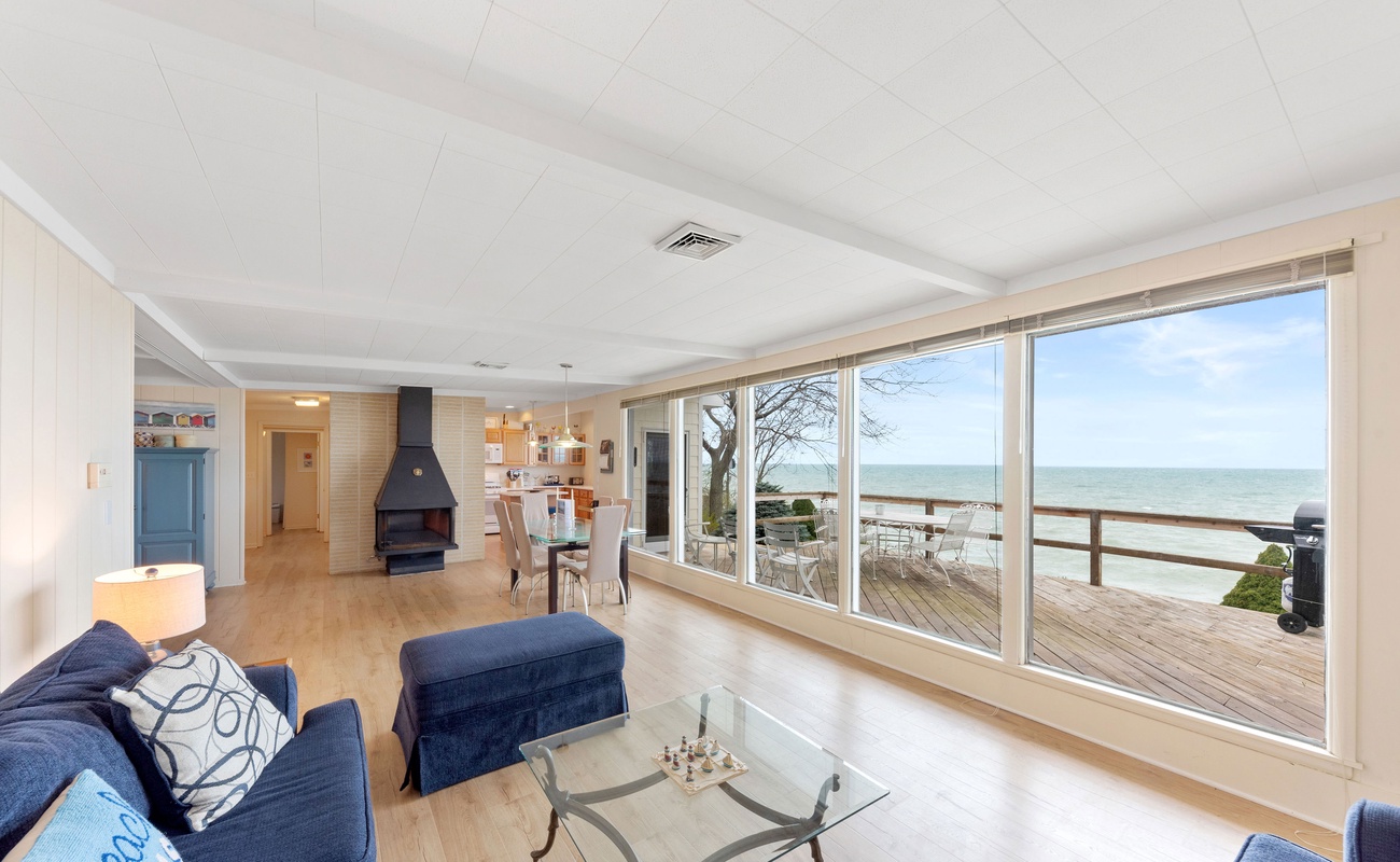 Sun filled living and dining area with expansive windows overlooking Lake Michigan and easy access to the private waterfront deck.