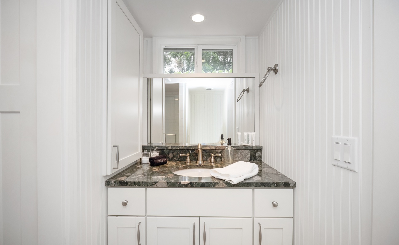 The lower-level bathroom has a tiled walk-in shower and custom vanity sink.