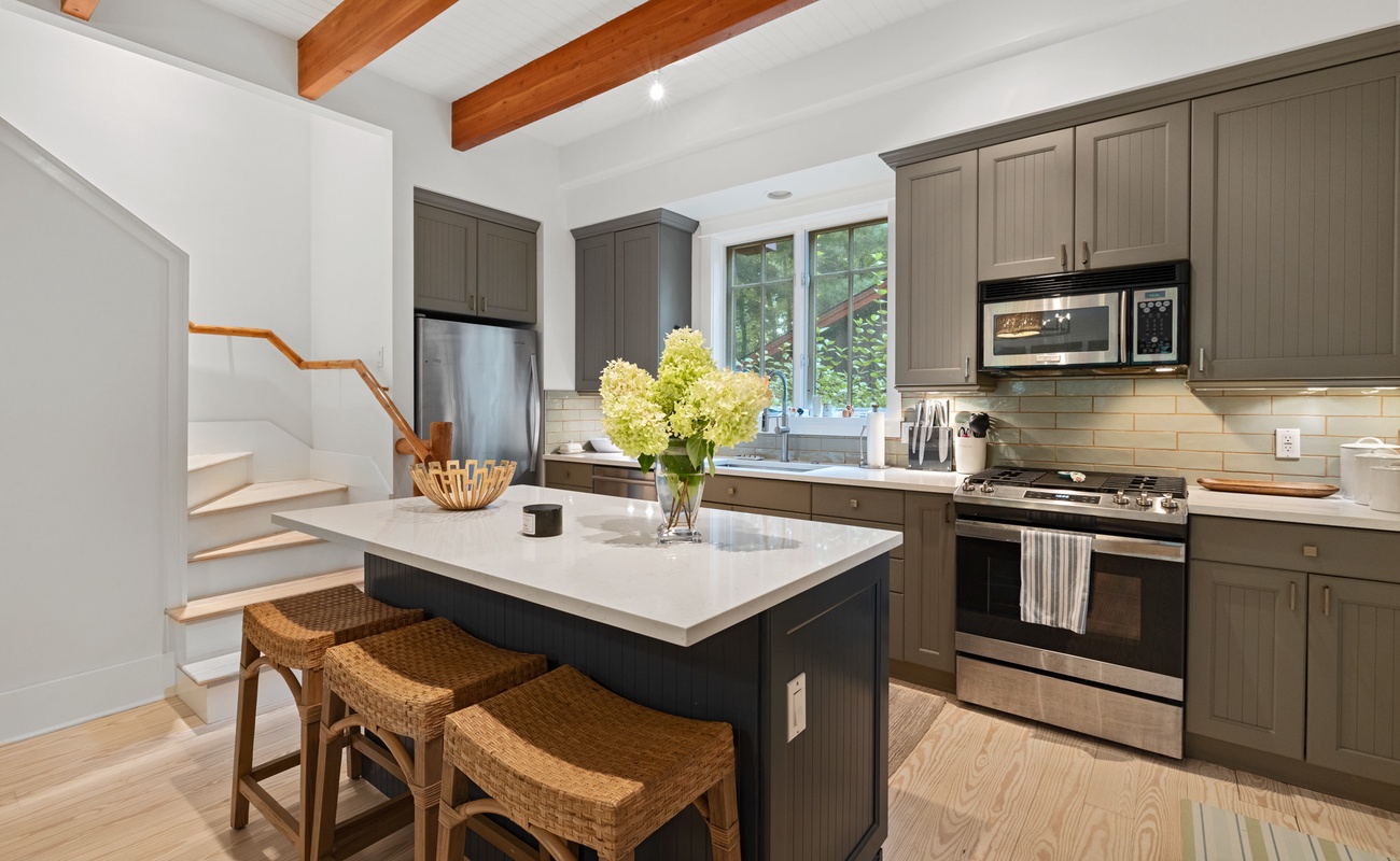 The well-equipped kitchen includes a center prep island with bar stools for entertaining,