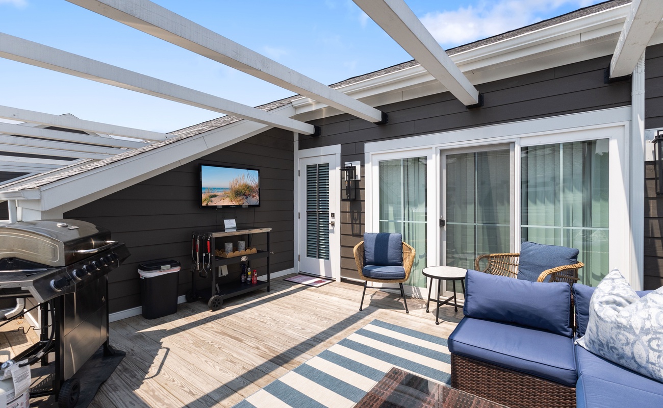 Lounge in style with grill, TV, and sunny rooftop vibes.