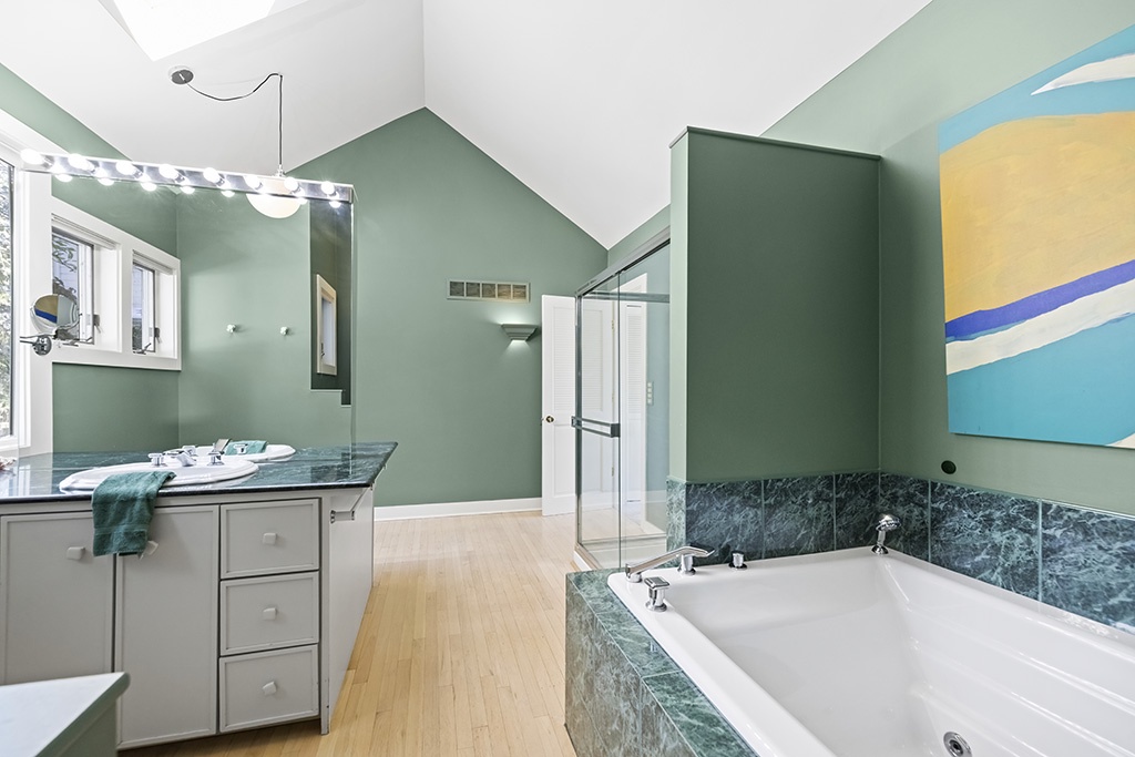 A spacious primary retreat with a soaking tub and calming green tones.