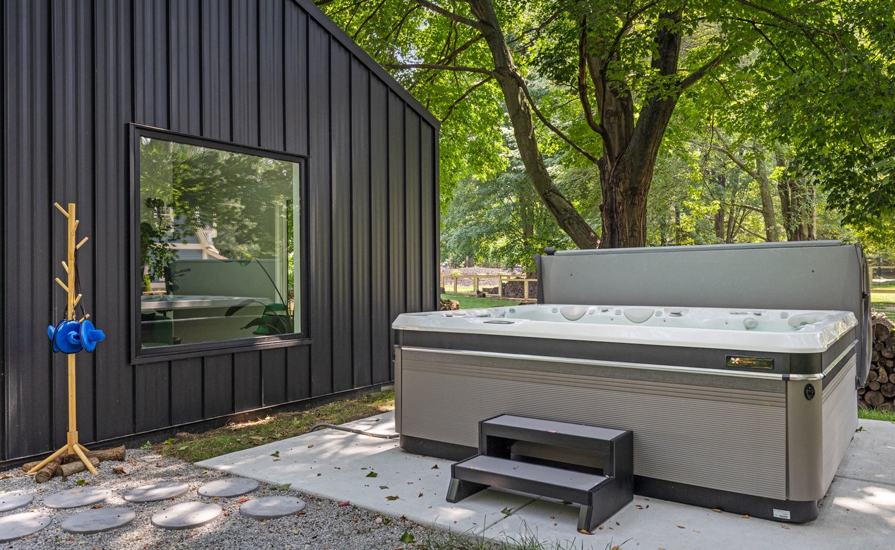 Surrounded by lush greenery, the hot tub offers a peaceful spot to relax and unwind.