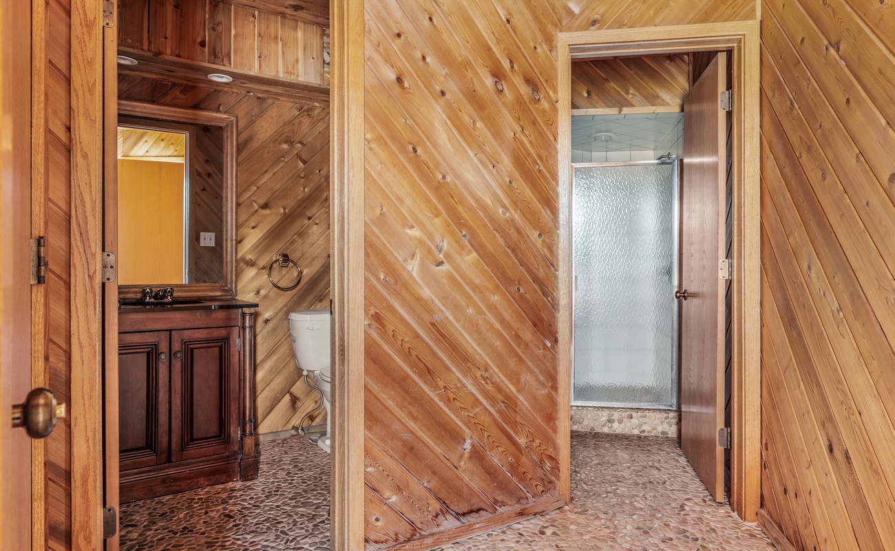 This classy bathroom highlights superb wood paneling and a tiled walk-in shower.