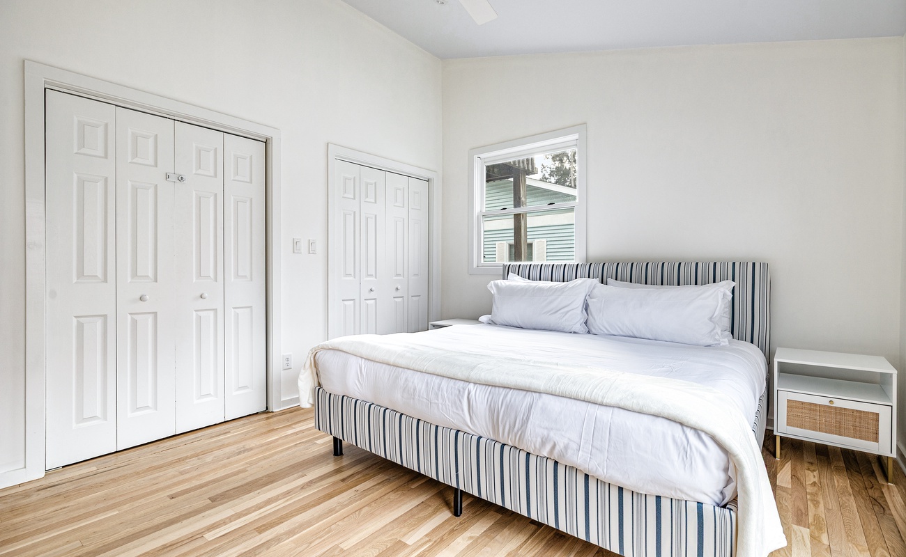 Breezy meets classy in this bright, airy bedroom! Striped charm, fresh linens, and pure comfort await!