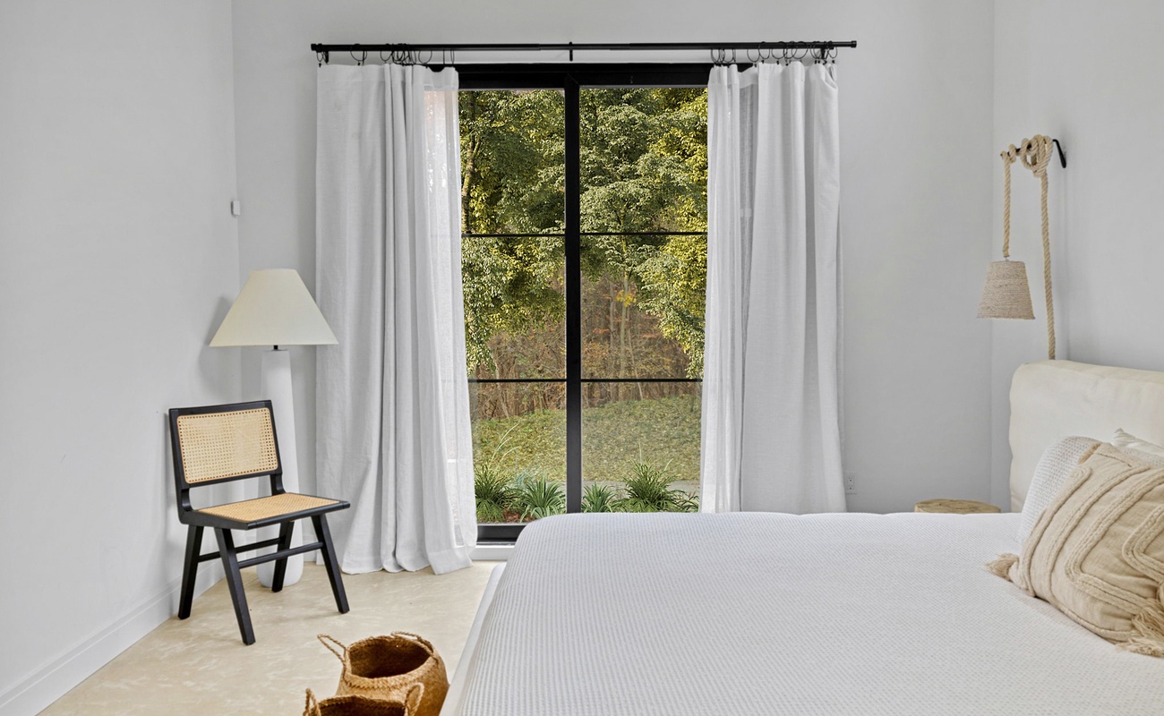 Wake up to serene garden views through floor-to-ceiling windows in your minimalist retreat, where crisp linens and natural light create pure tranquility.