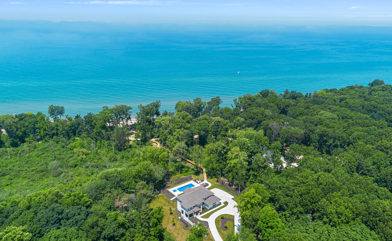 This aerial view captures the beauty of a house nestled amidst lush trees and serene waters.