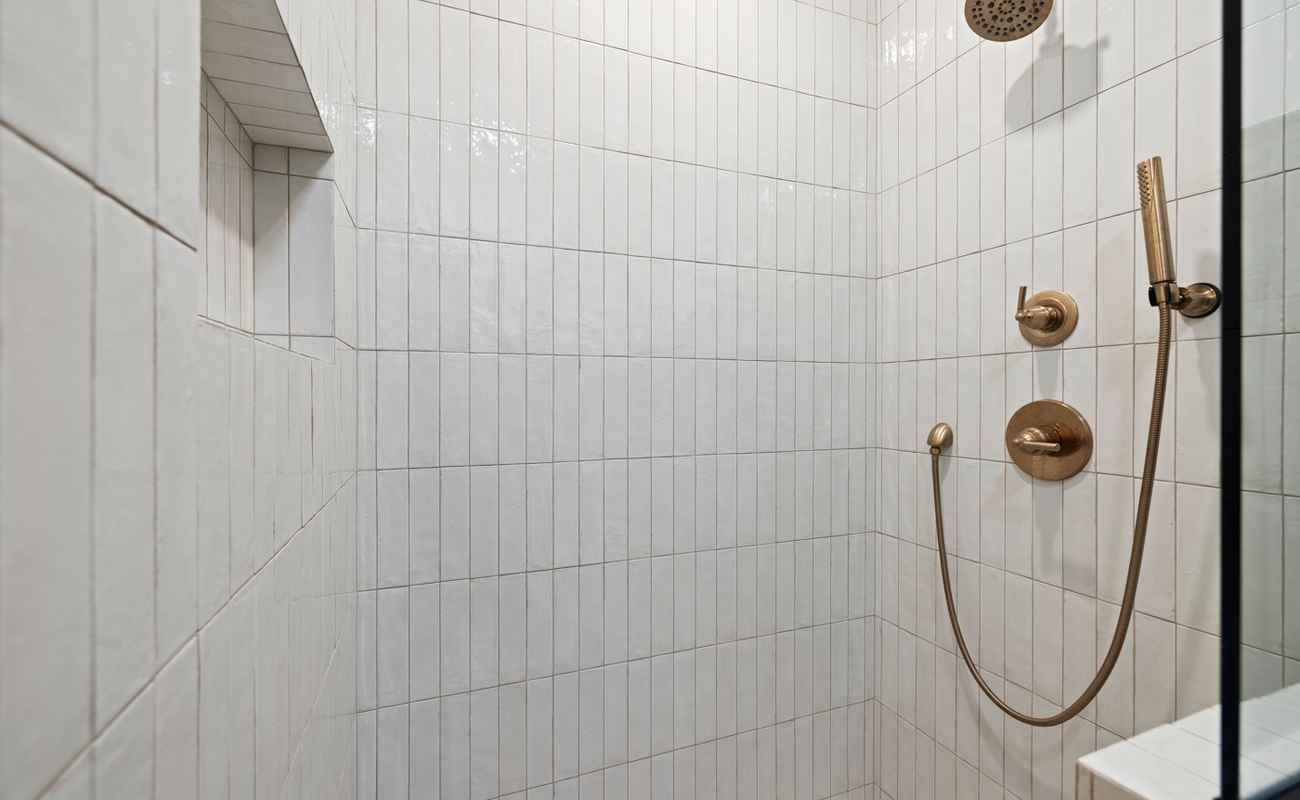 A modern walk-in shower with brass accents and quiet elegance.
