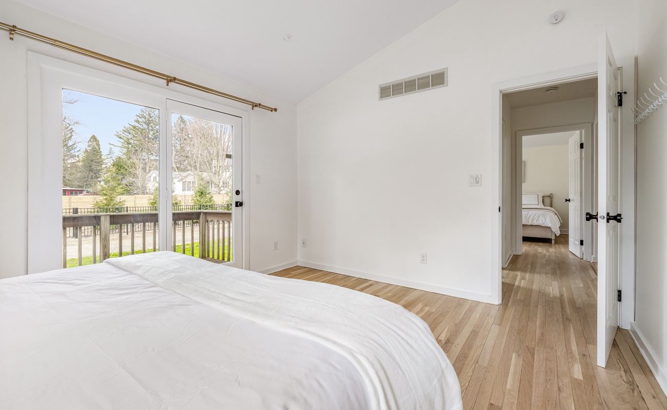 This room feels so bright and calming. The natural light from the sliding doors and the light wood floors give it such an airy, welcoming vibe. That peek into the second bedroom adds a nice sense of flow between the spaces.