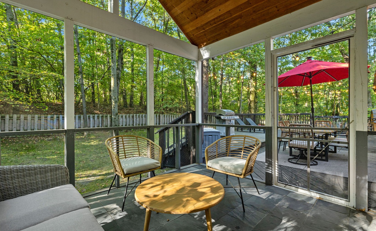 Just outside the screened-in porch is a relaxing deck, patio set + fenced yard.