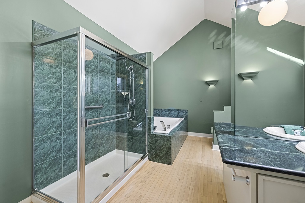 The Farmhouse’s primary bath pairs roomy comfort with calming green tones.