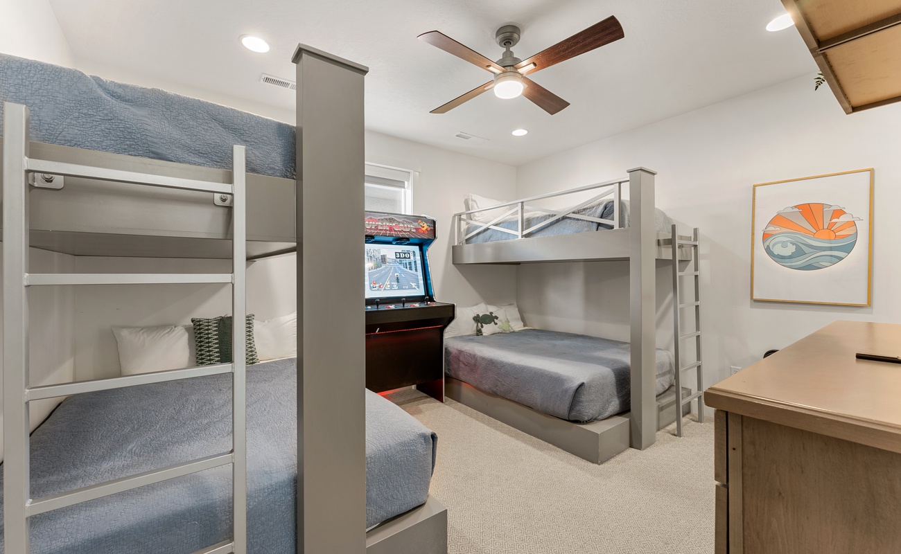 Your kids will love this fun bunk room with custom gray beds, ceiling fan, and dedicated gaming area for endless entertainment.