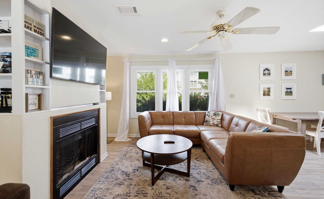 Bright, comfortable living space with a spacious sectional, fireplace, and large TV for relaxing after a day by the pool.