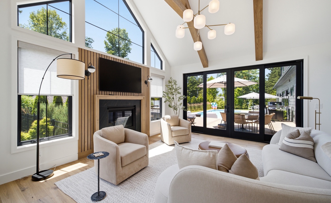 Bright living room with vaulted ceilings, a gas fireplace, and large windows overlooking the pool.