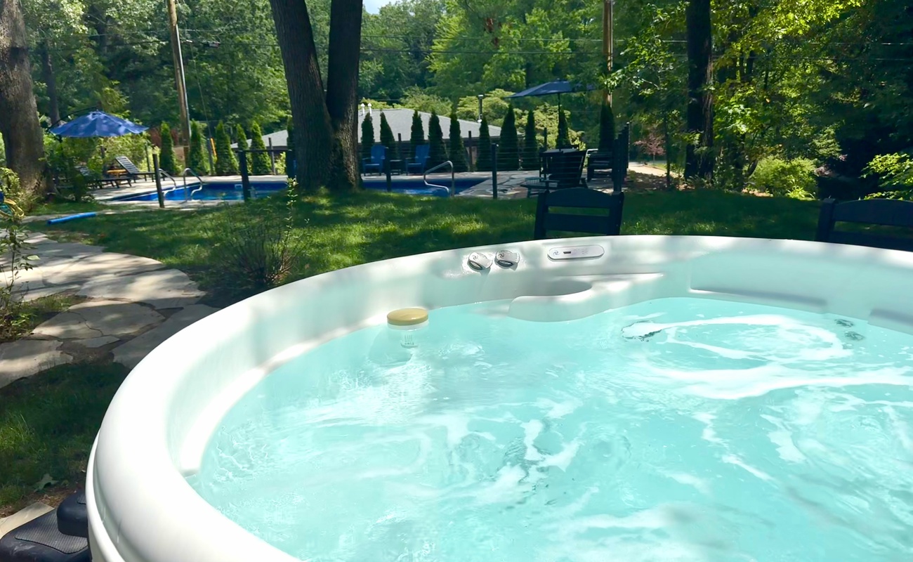 Unwind in the private hot tub overlooking the backyard, with the heated pool just steps away for the perfect day of relaxation and fun.