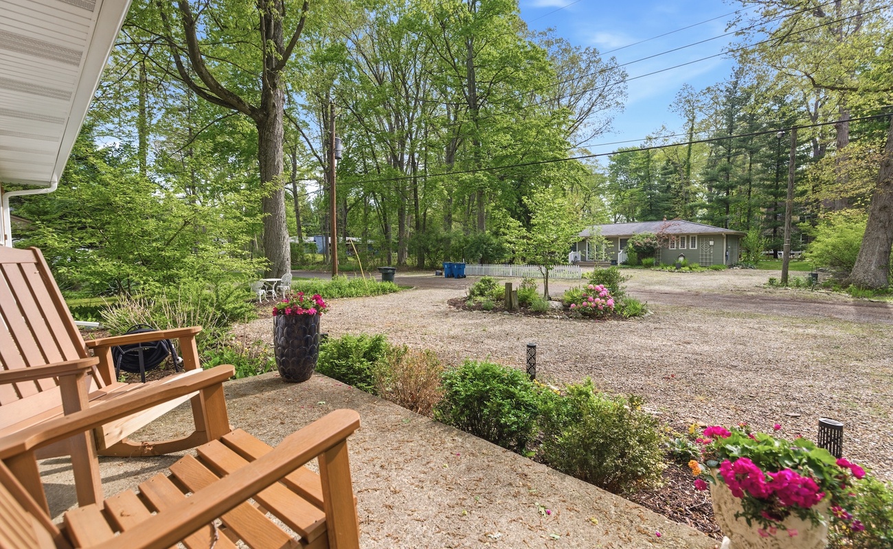 Peaceful front porch with rocking chairs overlooking the wooded property grounds
