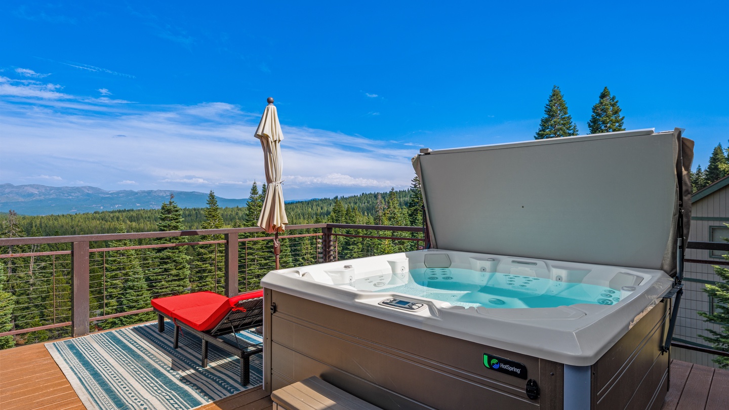 Soak in your private hot tub while taking in sweeping mountain and forest views under endless blue skies—your perfect mountain escape awaits.
