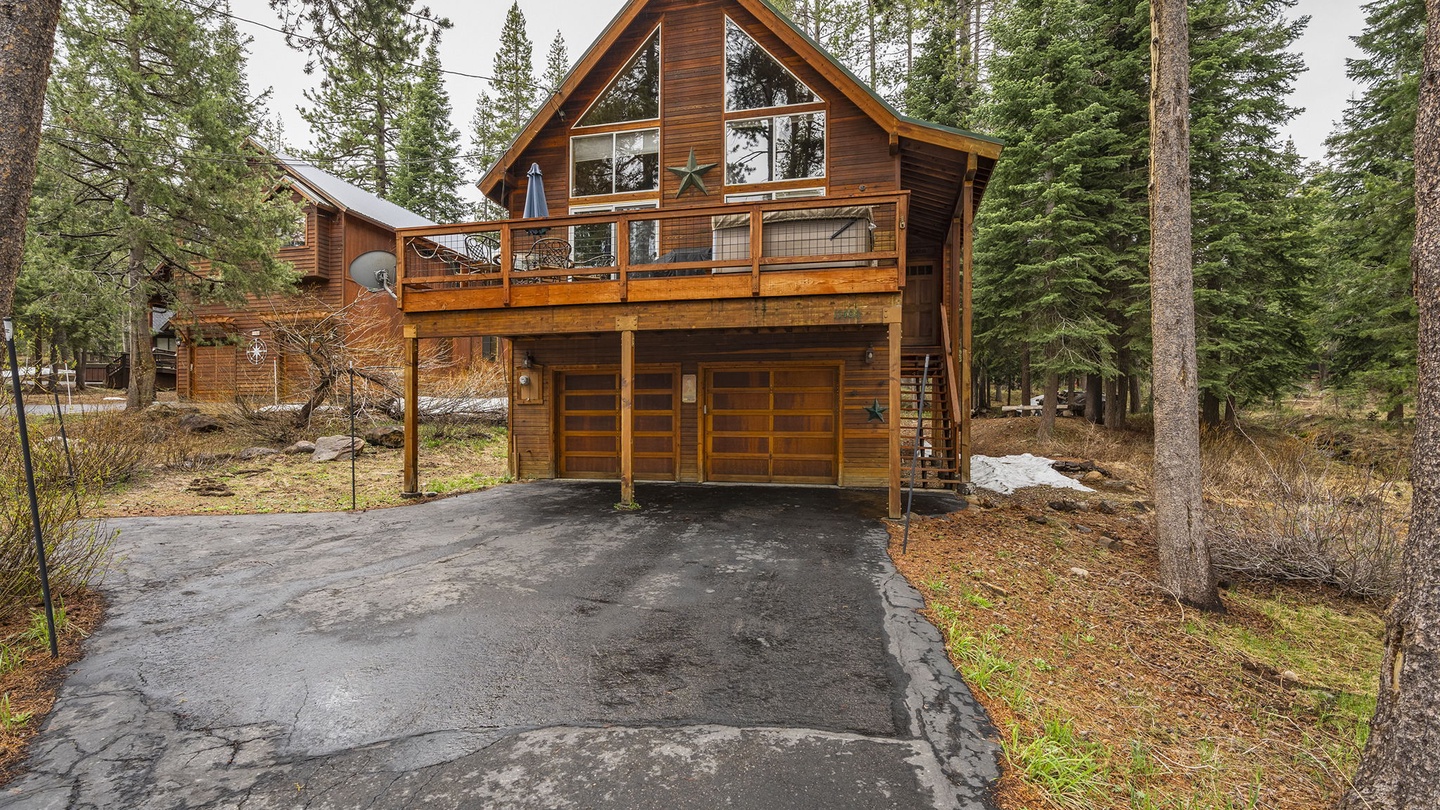 This charming mountain cabin features warm wood siding and a striking A-frame design, nestled among towering pines with convenient garage parking.