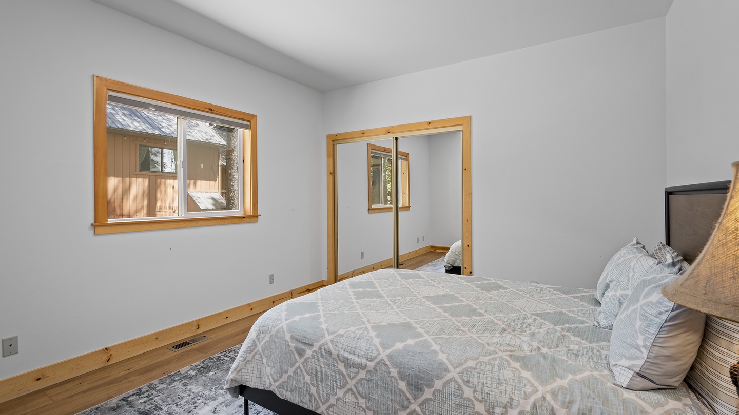 Settle into your cozy bedroom with warm wood accents and a peaceful view. Fresh white walls and natural light create a serene space for restful nights during your stay.