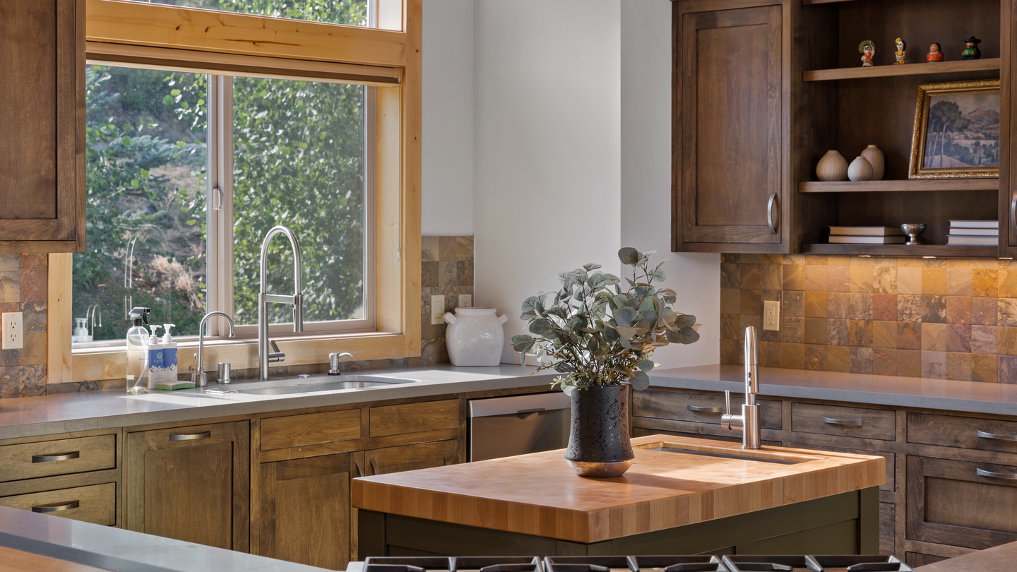 Your gourmet kitchen welcomes you with warm wood cabinetry, professional-grade appliances, and a butcher-block island—perfect for preparing meals while gazing at the lush greenery just outside the window.