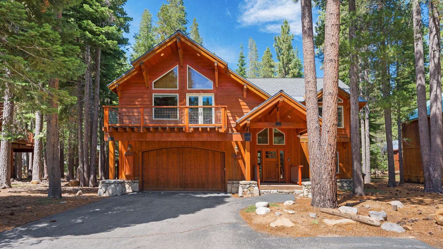 A charming mountain cabin nestled among towering pines, featuring warm wood siding, expansive windows, and plenty of natural forest light. The peaceful forest setting creates a serene retreat for your getaway.