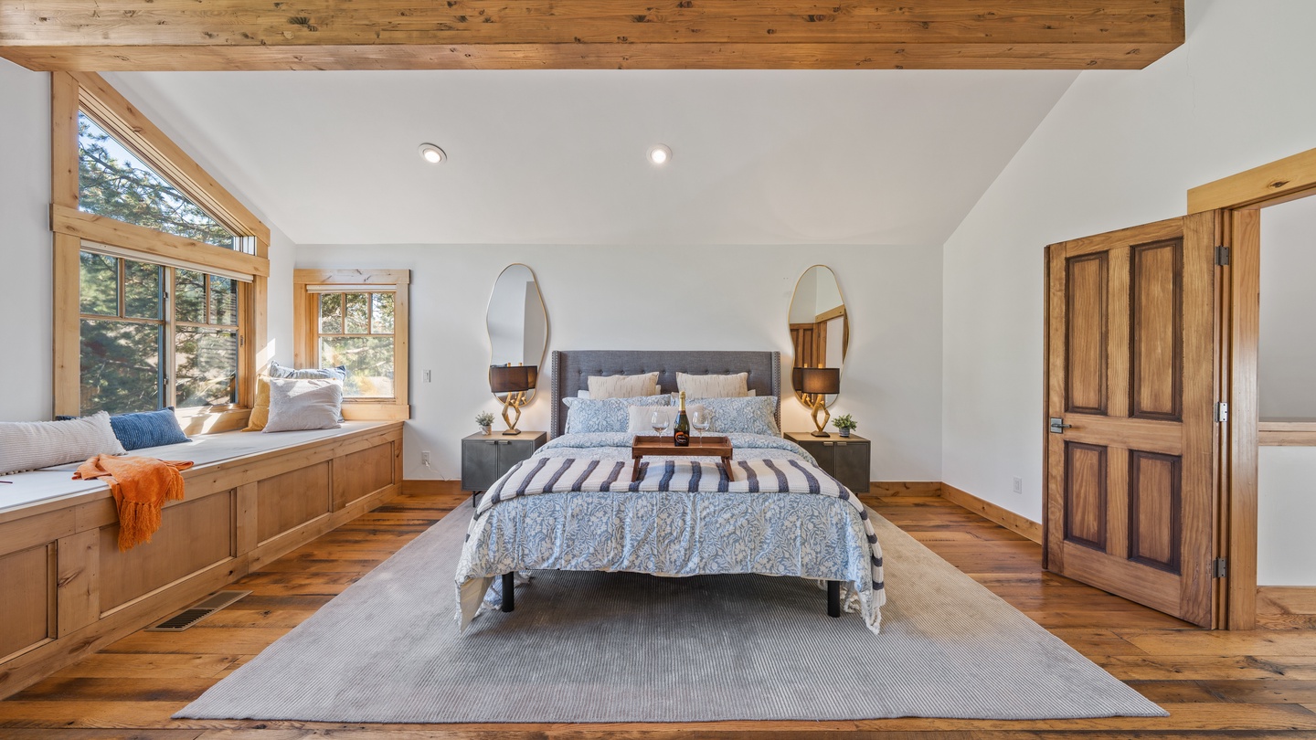 Wake up to natural light streaming through your private window seat overlooking the trees. This spacious bedroom blends rustic wood beams with elegant comfort for your perfect mountain retreat.
