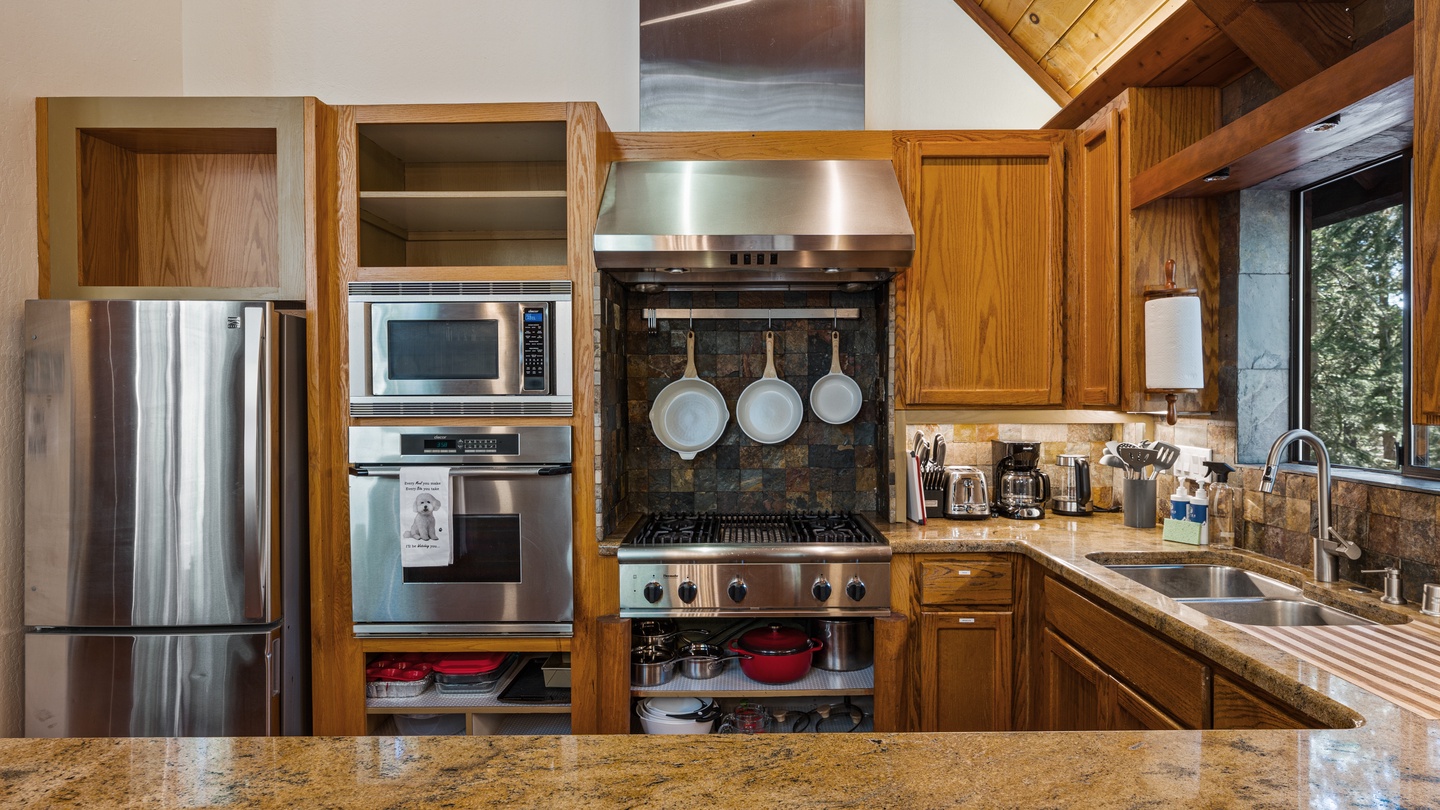 Cook up your favorite meals in this fully equipped kitchen, featuring modern stainless steel appliances, warm wood cabinetry, and abundant counter space for preparing delicious dinners together.