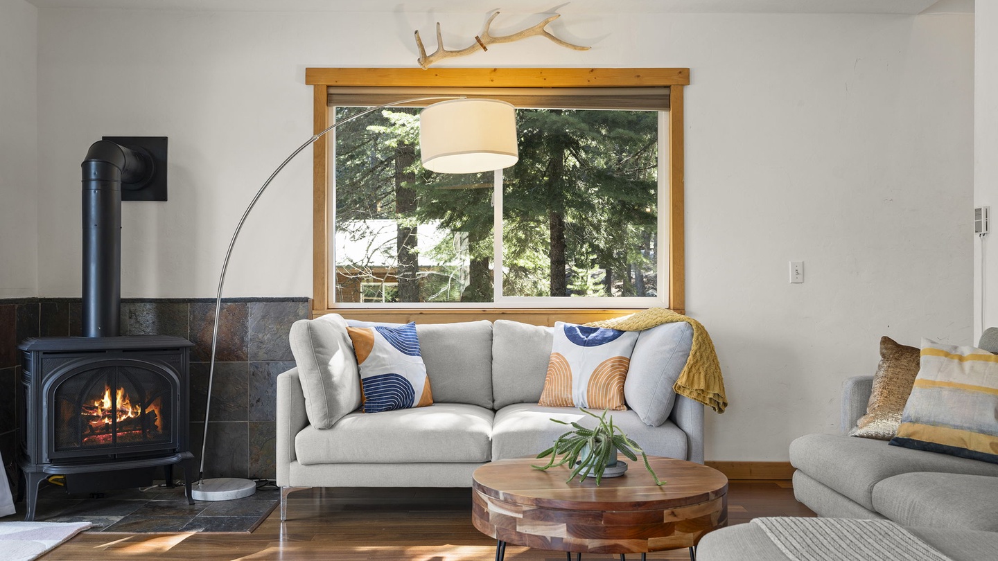 Cozy up in your bright living room with forest and lake views, crackling fireplace, and thoughtfully curated furnishings for perfect mountain retreat moments.