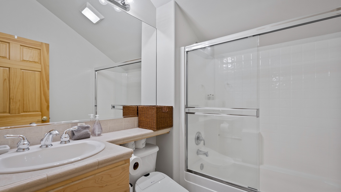 Step into a fresh, spotless bathroom with everything you need—bright vanity lighting, plush rolled towels, a tub-shower combo, and warm wood accents that make it feel inviting and ready for your stay.