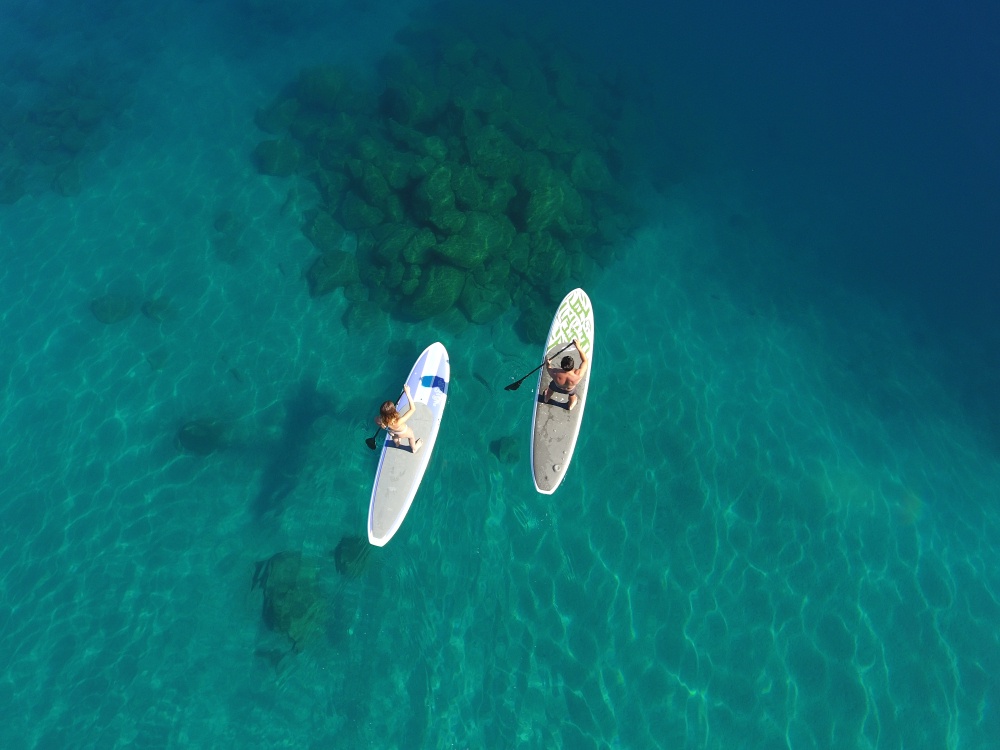 Aerial view of crystal-clear turquoise waters with two paddle boarders exploring the pristine coastal area near the property.