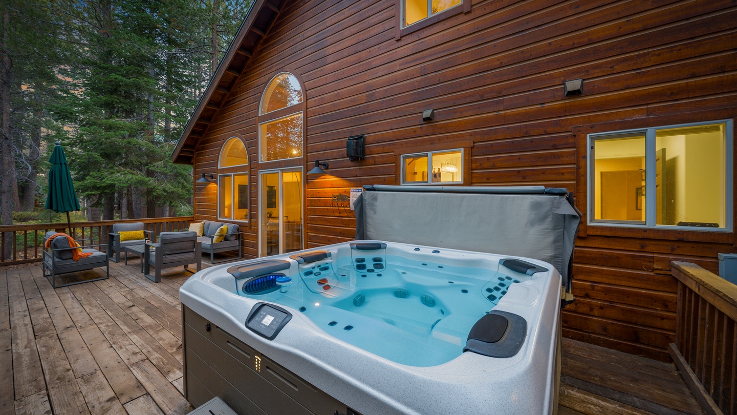Soak beneath the pines in your private hot tub, perfectly positioned on the deck where warm glowing windows invite you back inside the cozy wood cabin when you're ready.