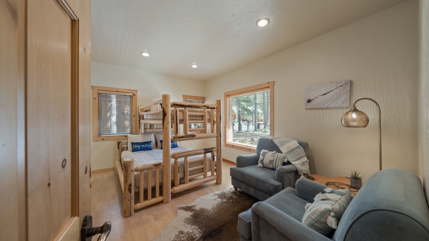 Cozy bedroom with rustic log bunk beds and a comfortable lounge area where you can unwind after your mountain adventures.