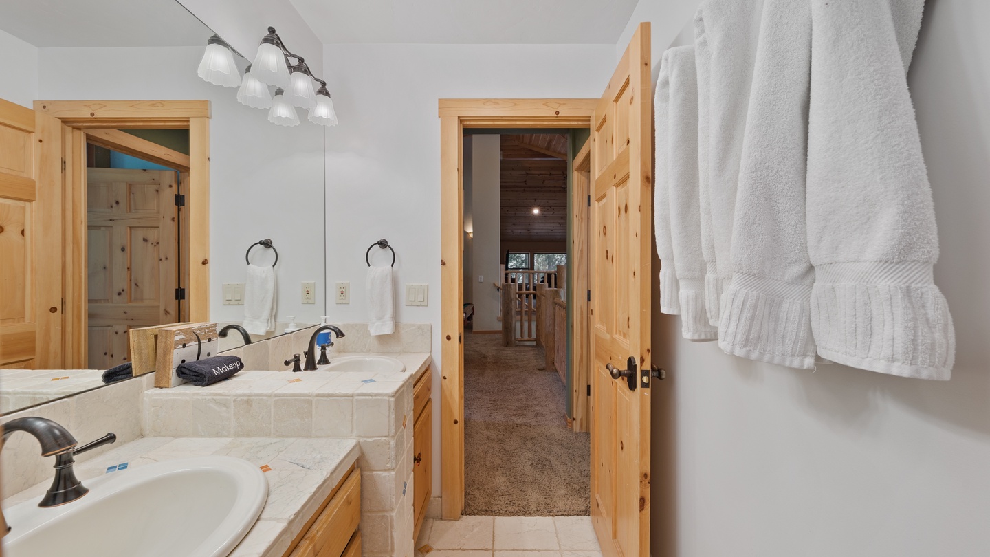 Freshen up in your spacious double-vanity bathroom, complete with plush towels and charming rustic pine accents for a cozy mountain retreat feel.