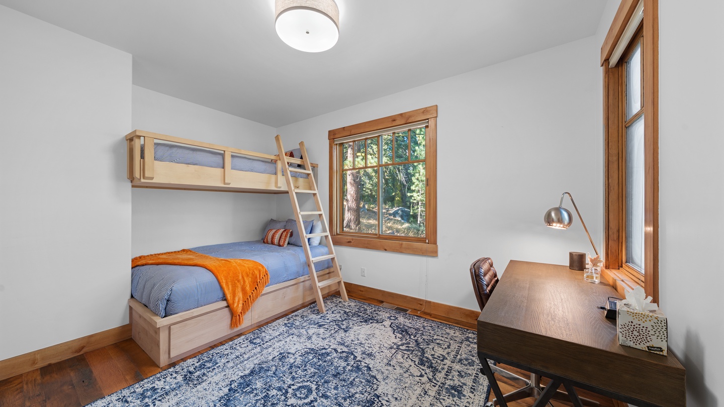 Gather the kids for a cozy night in this charming bunk room, where warm wood tones and a peaceful forest view set the stage for restful mountain dreams.