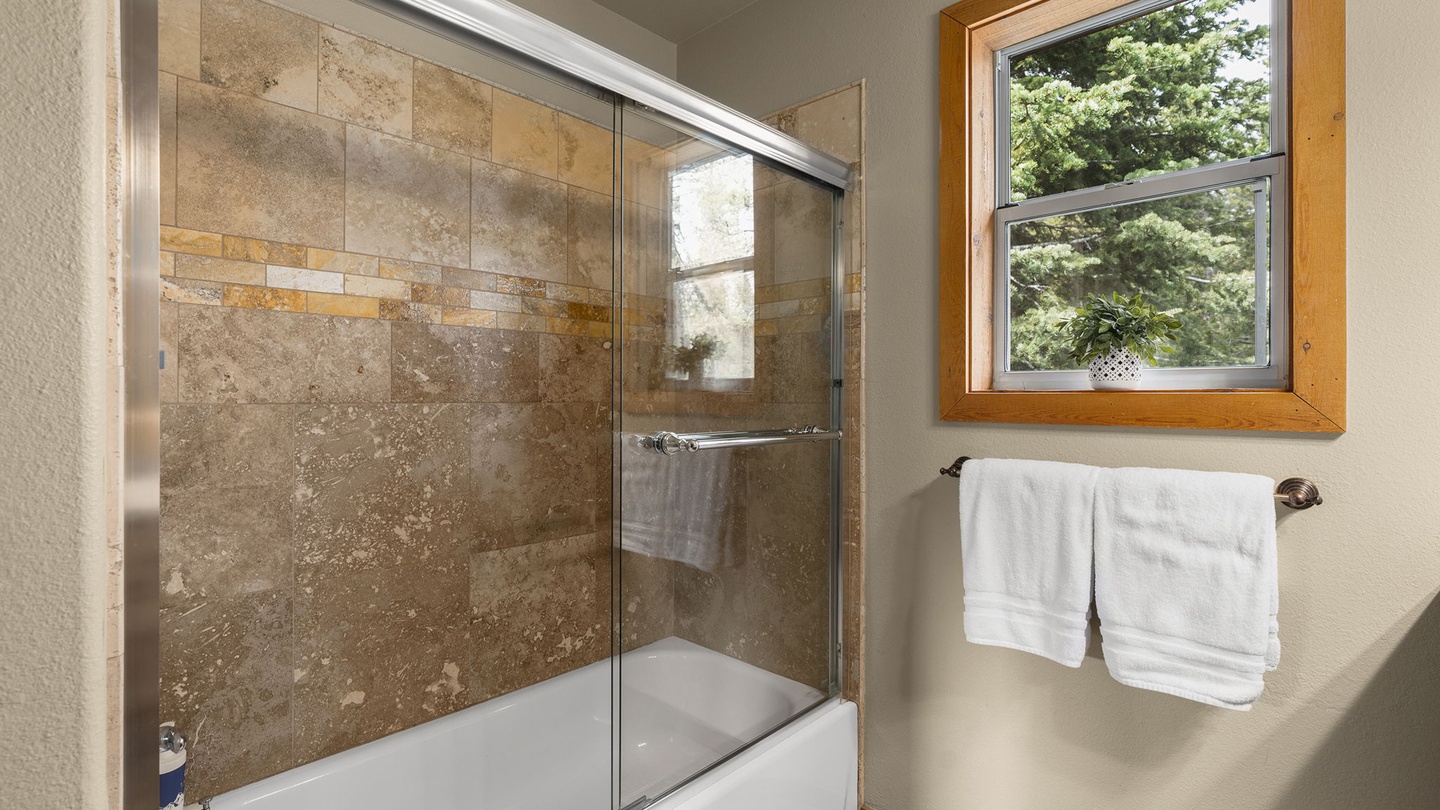 Unwind in your stylish bathroom with elegant stone tile walls and glass shower doors that make your space feel both luxurious and spacious.