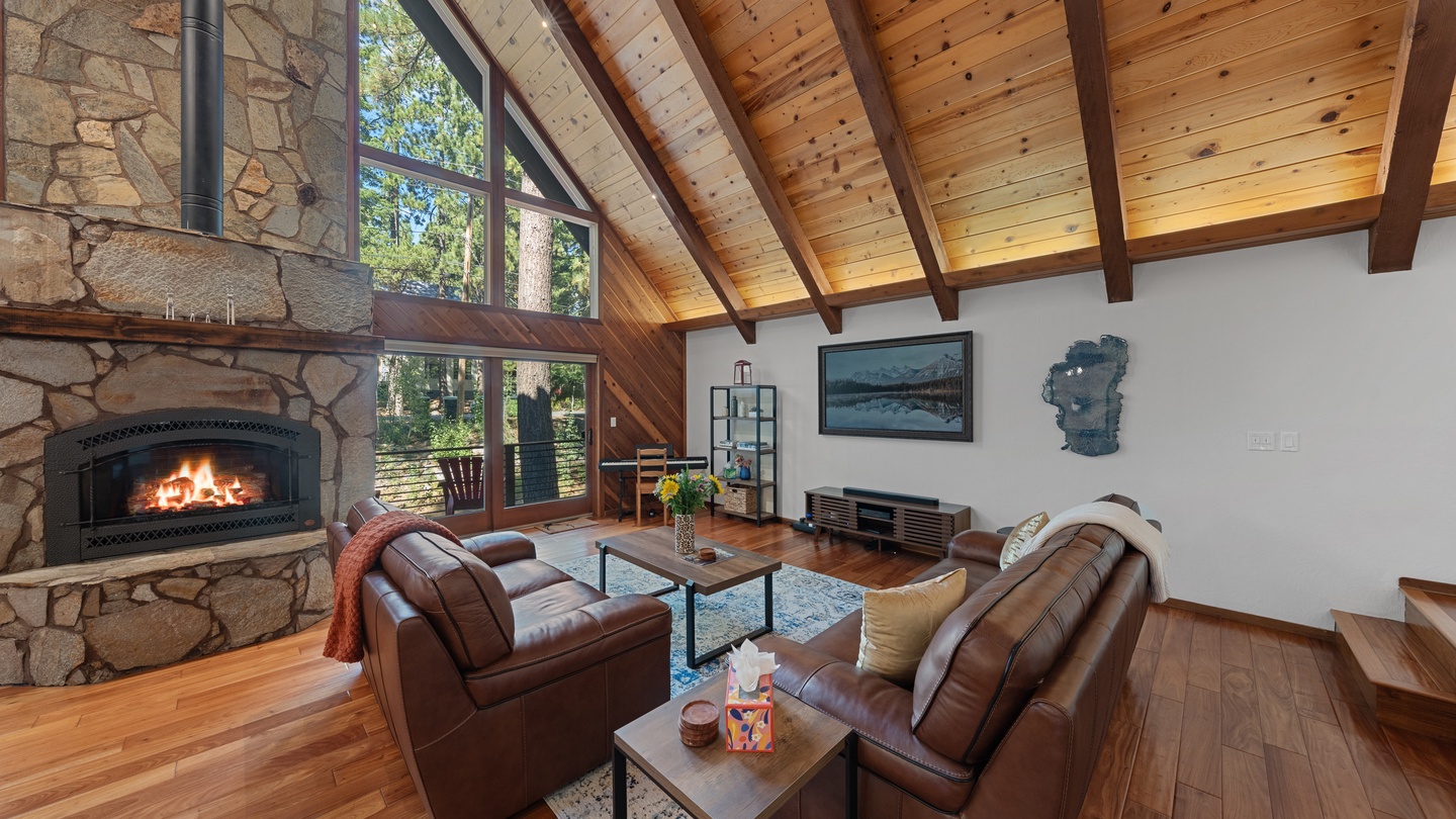 Unwind by the crackling fireplace in this vaulted living room, where warm wood beams and forest views create your perfect mountain retreat.