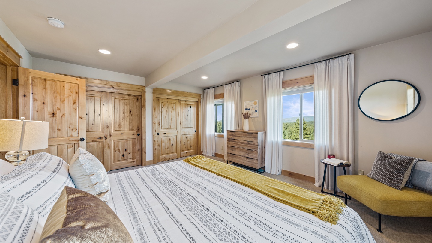 Drift off in this serene bedroom where warm wood tones and soft linens create your restful retreat. Morning light and scenic views pour through the windows, welcoming you to a peaceful mountain escape.