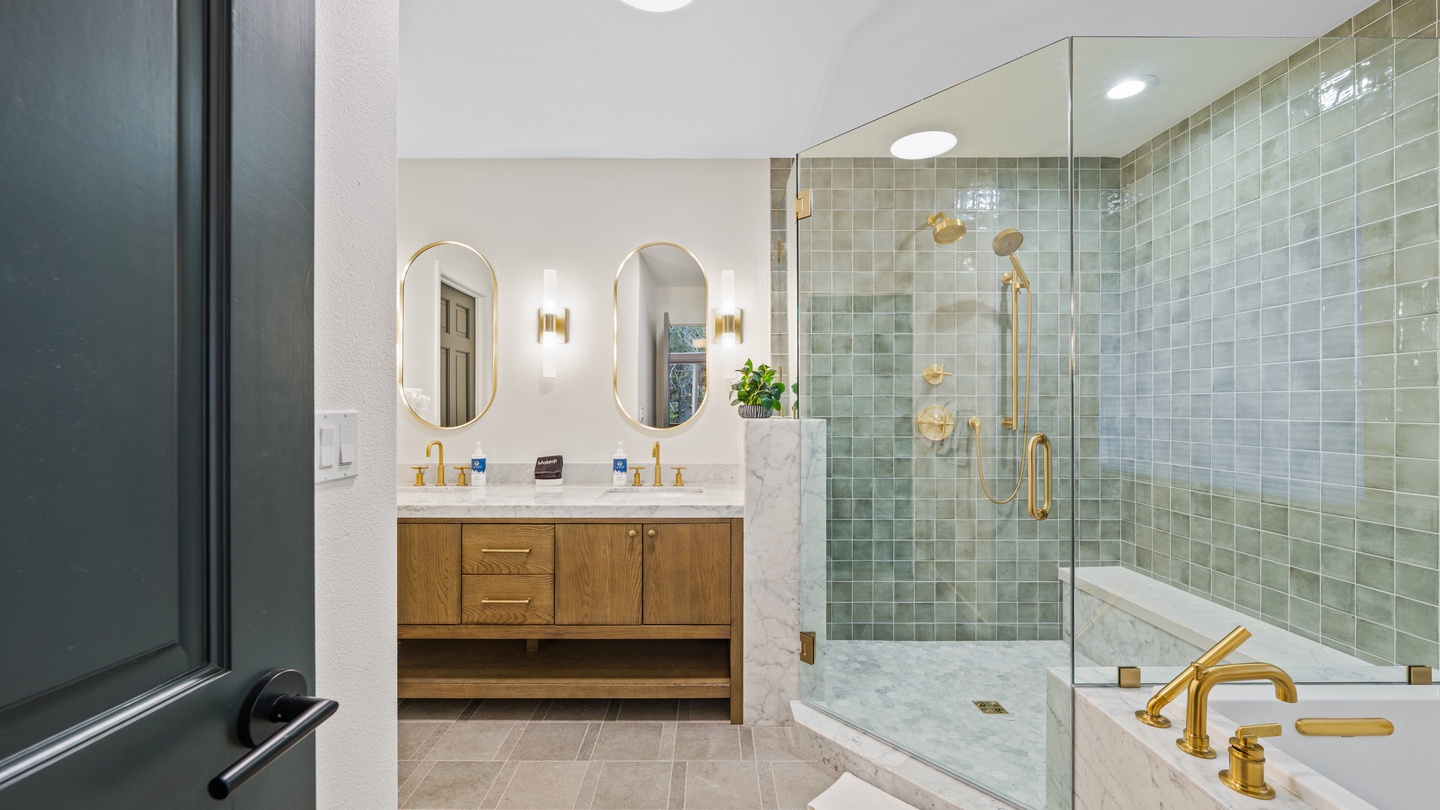Step into your private spa sanctuary, where sage-green tiles shimmer under soft lighting and gleaming gold fixtures add elegance to every touch. The spacious walk-in shower and soaking tub invite you to unwind at your own pace.