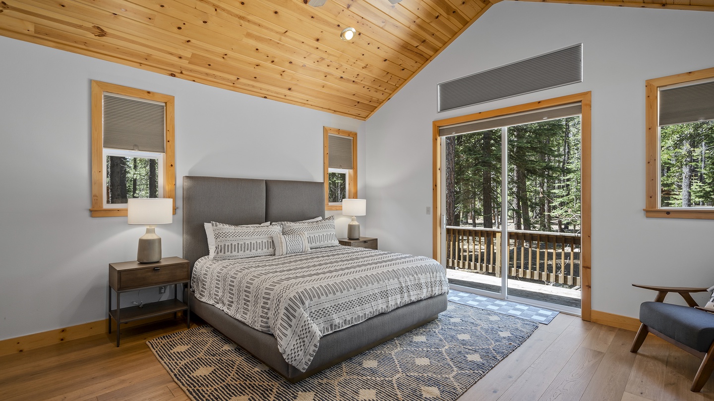 Wake up in your serene bedroom under soaring wood ceilings, where natural light streams through large windows and sliding glass doors open to your private balcony overlooking the forest.