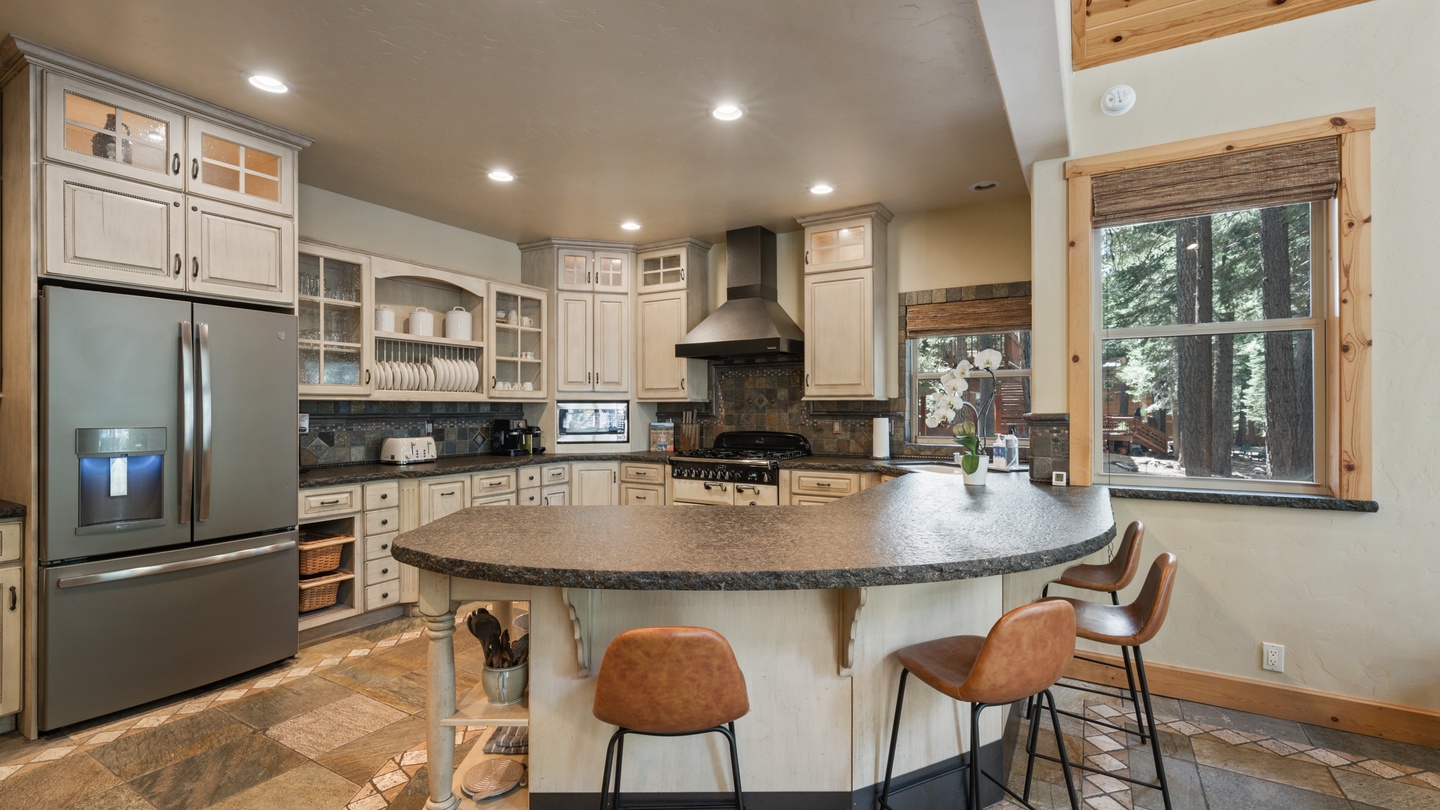Gather around the spacious granite island where morning coffee and evening conversations feel right at home. Towering windows frame peaceful forest views while abundant cabinetry keeps everything within reach.