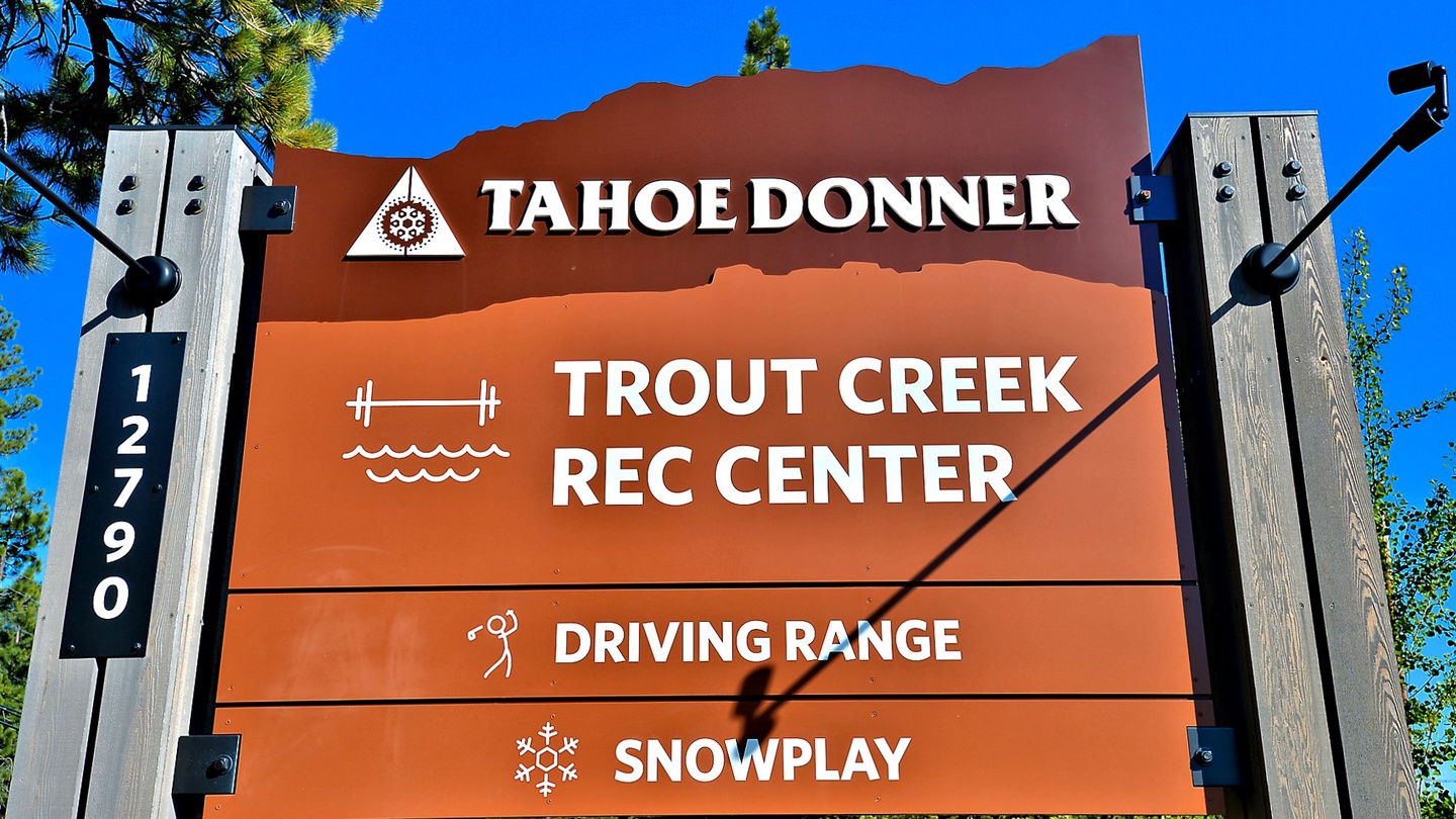 Directional signage marking the entrance to Tahoe Donner recreation facilities, including the Trout Creek Rec Center, driving range, and snowplay area.