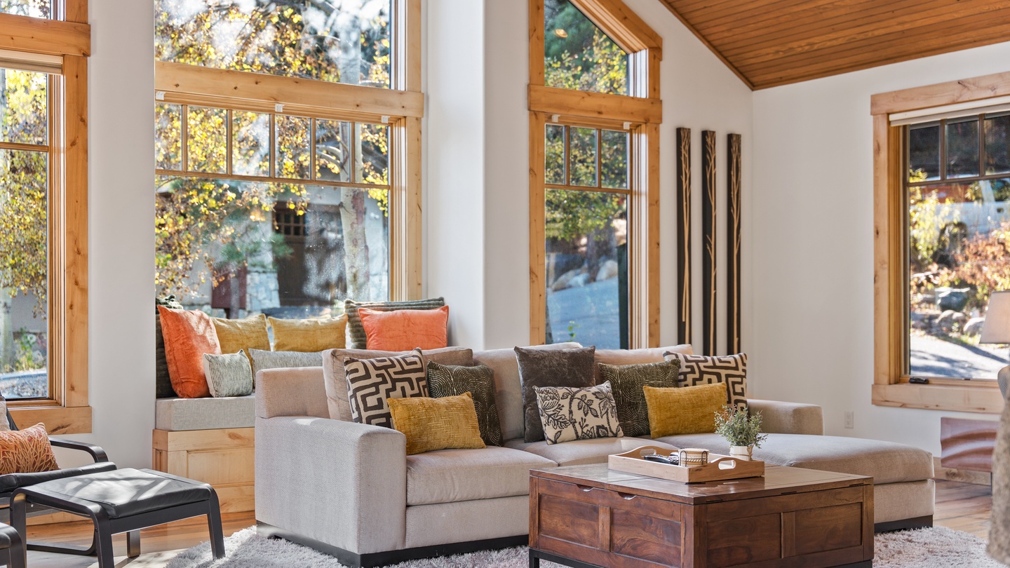 Sink into plush cushions surrounded by warm wood and sunlight streaming through tall windows. Your mountain retreat awaits with cozy seating and natural views all around.