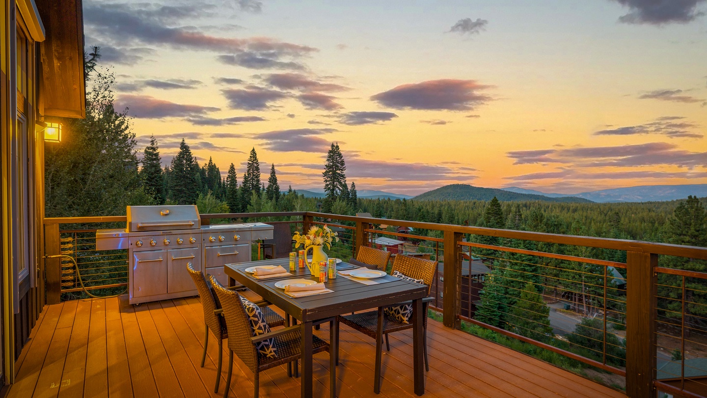Elevated deck offers sweeping views of forested hillsides and a stunning sunset sky, featuring an outdoor dining setup and built-in BBQ for effortless al fresco entertaining.