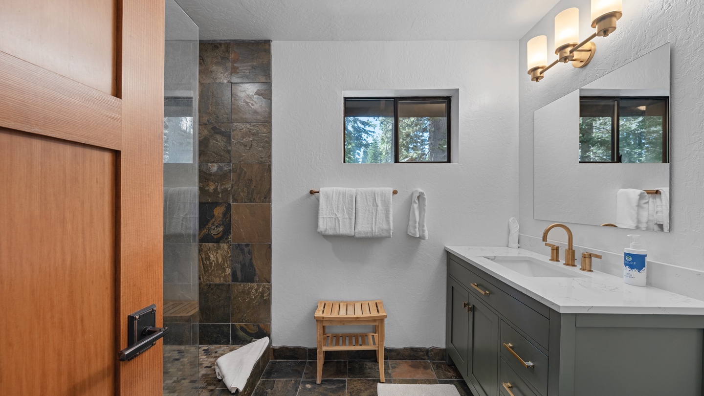 Refresh and unwind in your modern bathroom, where natural slate floors meet crisp white counters and a spacious walk-in shower beckons after a long day of adventure.